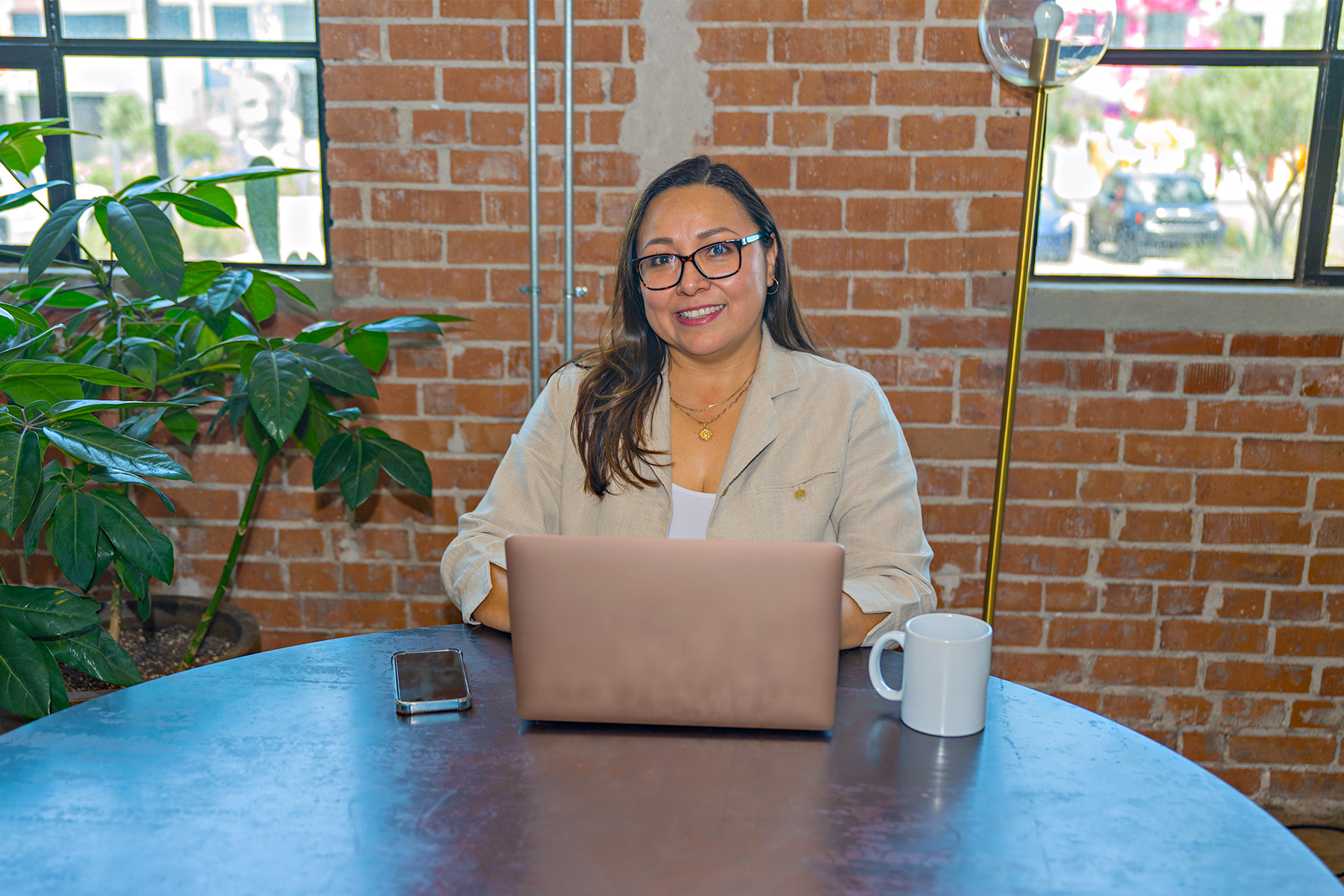 Woman sitting in front of laptop with cell phone and coffee cup on the desk