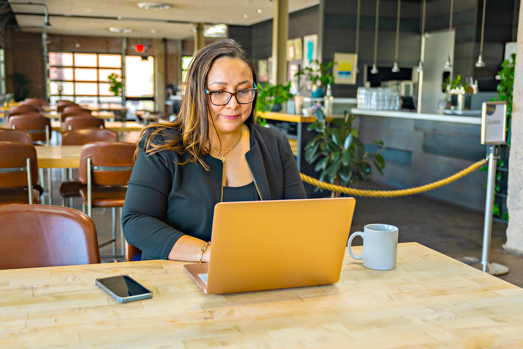 Woman typing on laptop sitting at a restaurant